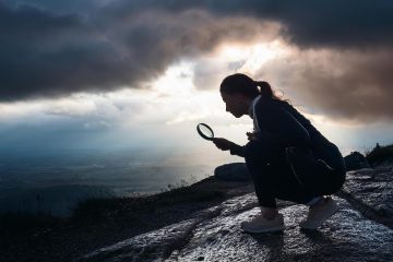 person using magnifying glass on mountainside with stormy clouds, generated by Adobe Firefly