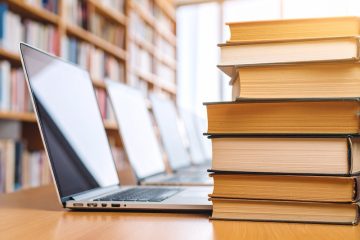 laptops and pile of book on desk in library, generated by Adobe Firefly