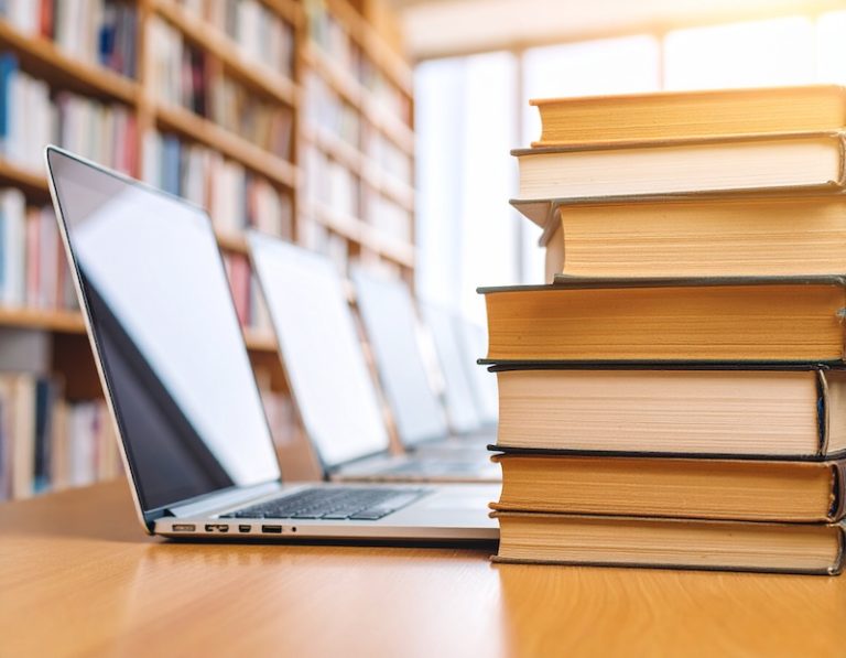 laptops and pile of book on desk in library, generated by Adobe Firefly